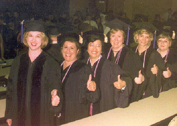Group of Nursing students in graduation caps and gowns thumbs up